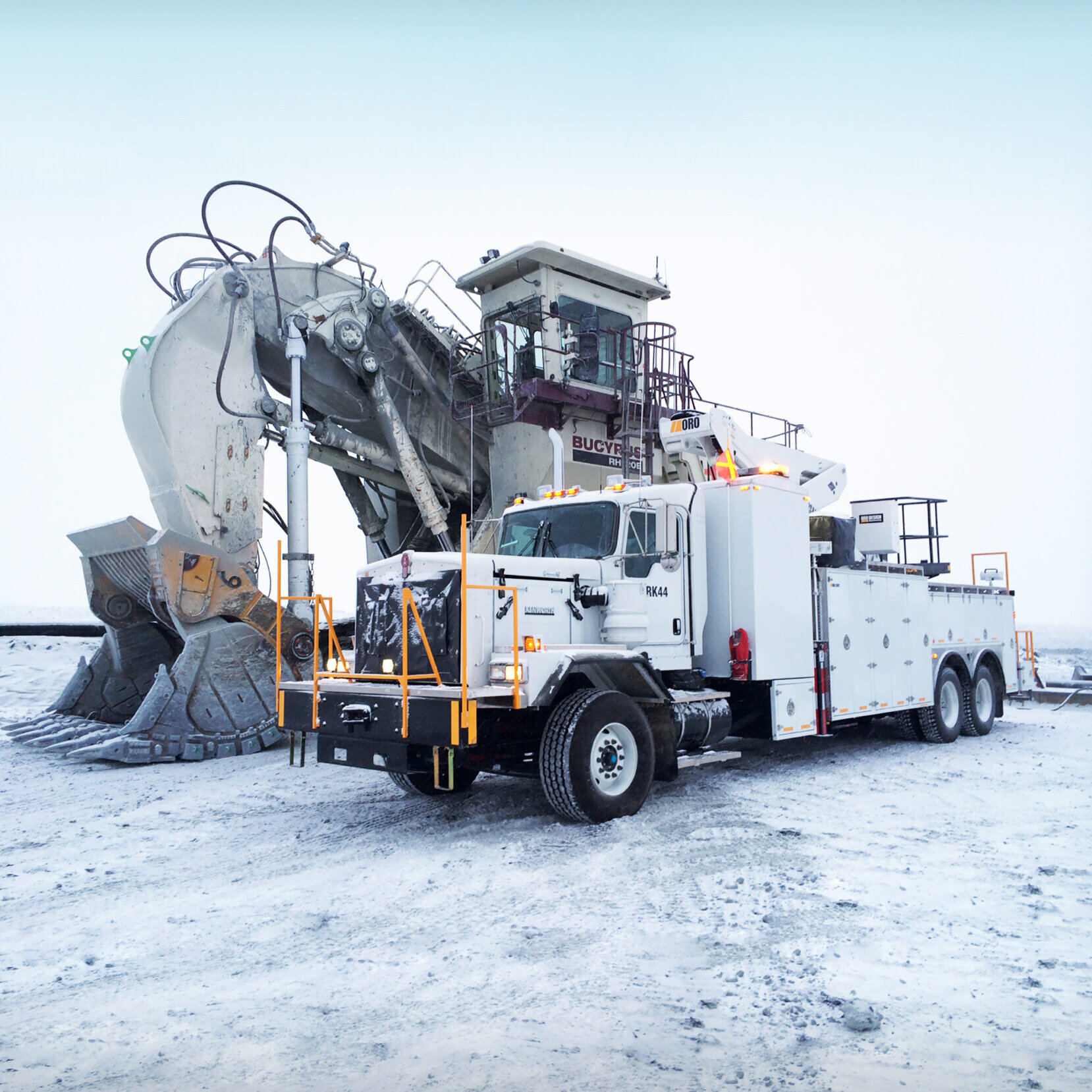 ORO 20M8 mechanic service truck body in white, with Versalift manlift and Stellar 12630 telescopic mechanic crane on Kenworth C500 next to a Bucyrus RH400 excavator.